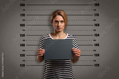 Criminal mugshot. Arrested woman with blank card against height chart photo