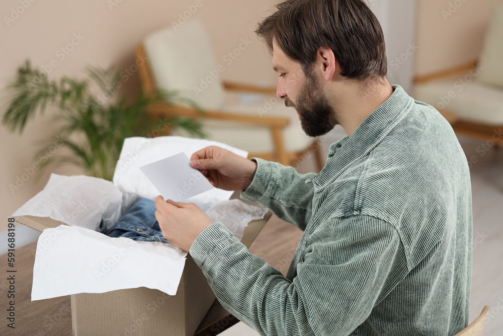 Man with greeting card near parcel at home. Internet shopping Man with greeting card near parcel at home. Internet shopping