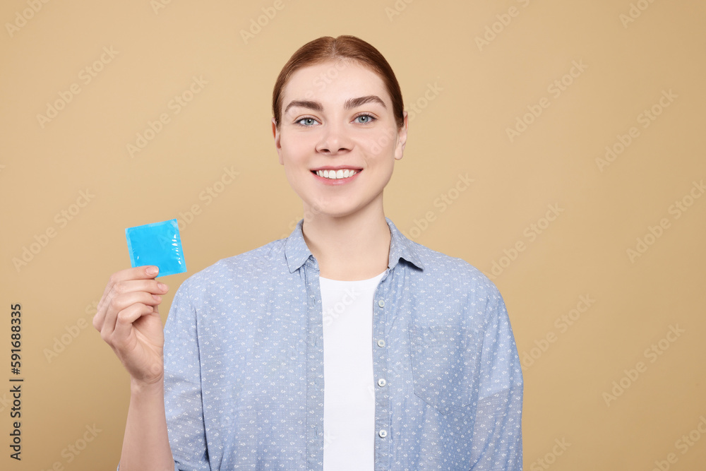 Woman holding condom on beige background. Safe sex Woman holding condom on beige background. Safe sex