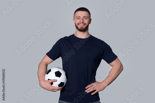 Athletic young man with soccer ball on light grey background