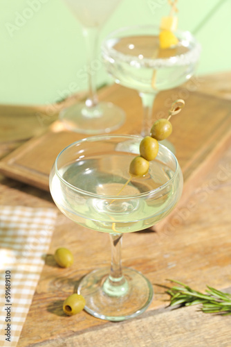 Glass of tasty martini and olives on wooden table