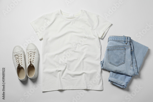 Stylish t-shirt, jeans and sneakers on white background, flat lay