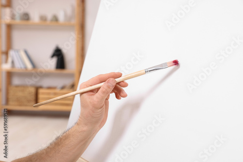Man painting on canvas in studio, closeup