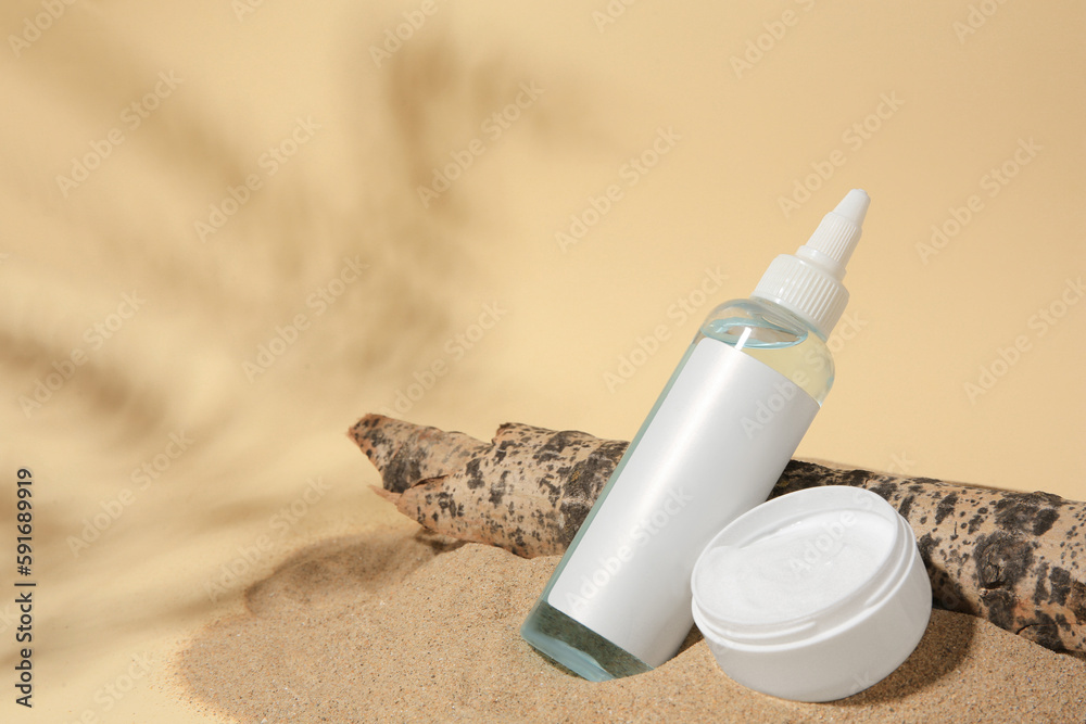 Cosmetic products and tree bark on sand against beige background. Space for text Cosmetic products and tree bark on sand against beige background. Space for text