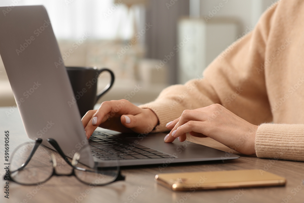 Woman working with laptop at wooden desk indoors, closeup Woman working with laptop at wooden desk indoors, closeup