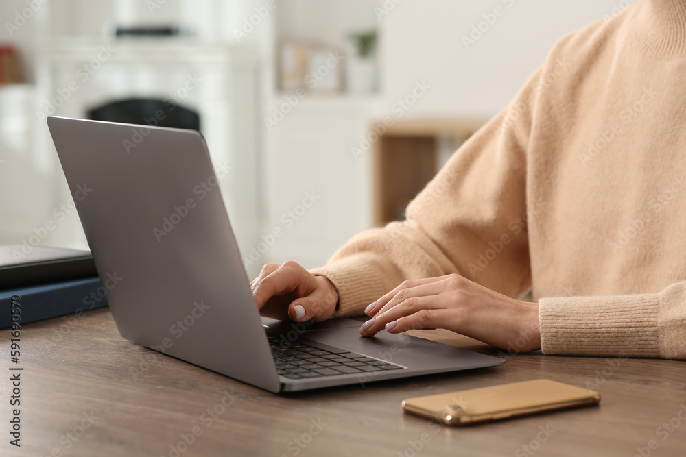 Woman working with laptop at wooden desk indoors, closeup Woman working with laptop at wooden desk indoors, closeup