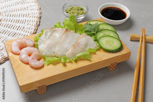 Sashimi set served with cucumber, lettuce, soy sauce and vasabi on light grey table photo