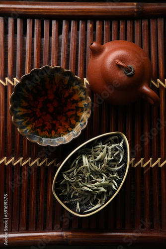 Aromatic Baihao Yinzhen tea and teapot on wooden tray, flat lay. Traditional ceremony photo