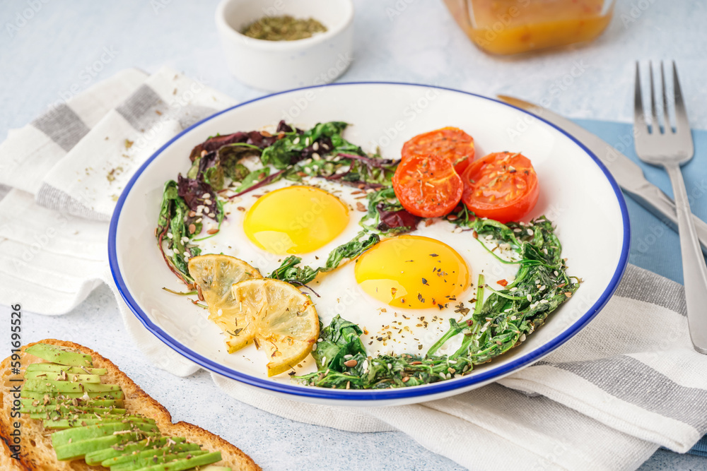 Plate with tasty fried eggs, salad and avocado sandwich on light background