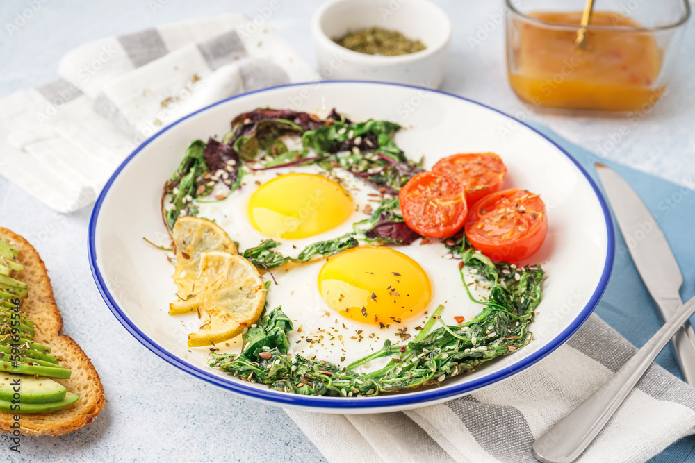 Plate with tasty fried eggs, salad and avocado sandwich on light background Plate with tasty fried eggs, salad and avocado sandwich on light background