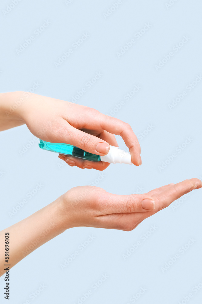 Woman applying sanitizer on grey background