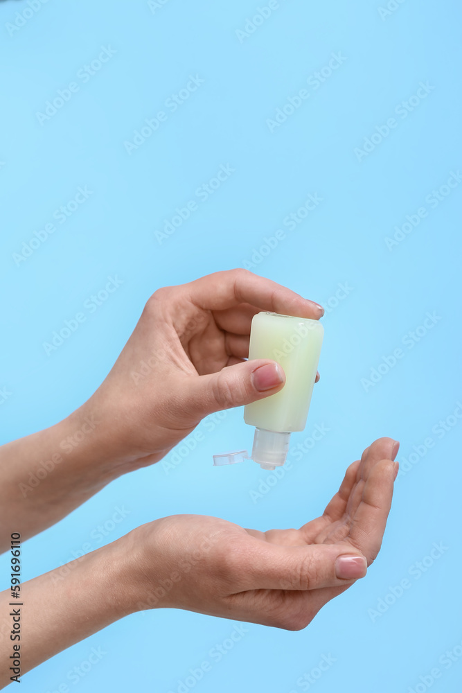 Woman applying sanitizer on blue background Woman applying sanitizer on blue background