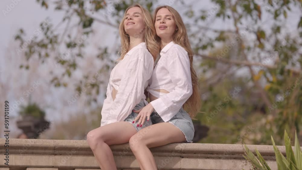 Identical twins posing in a park Identical twins posing in a park