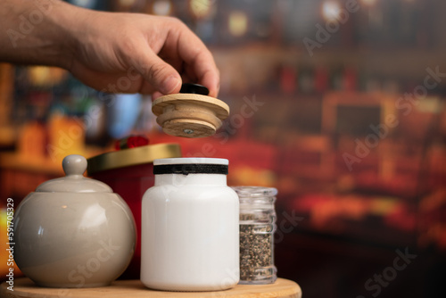 Mugs of sugar while a hand open a containers style vintage over a table in night restaurant