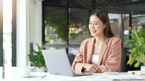 Successful business woman looking at laptop screen and winning