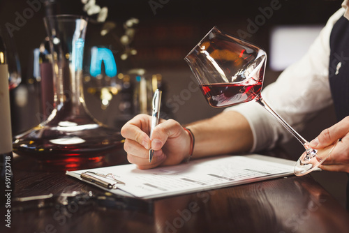 Faceless person hands hold stem glass with red wine.