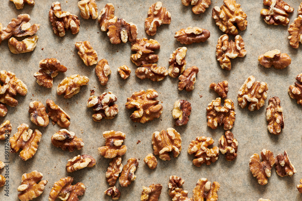 Toasted walnuts on parchment paper on a sheet pan. Toasted walnuts on parchment paper on a sheet pan.