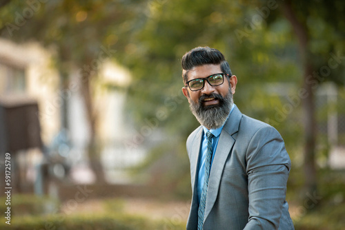 Confident Indian corporate man giving expression at park.