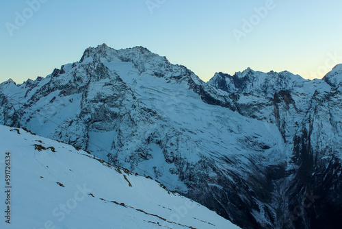 Snow covered Caucasus mountains with Mt. Belalakaya at winter cloudy day. Panoramic view from Mt. Mussa-Achitara slope, Karachai-Cherkess, Russia. photo