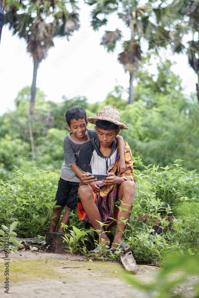 two rural kids are smiling holding smartphones against a forest background two rural kids are smiling holding smartphones against a forest background