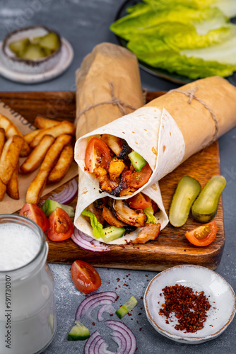 Chicken doner wraps served with chips, pickles and salad on a wooden board. photo