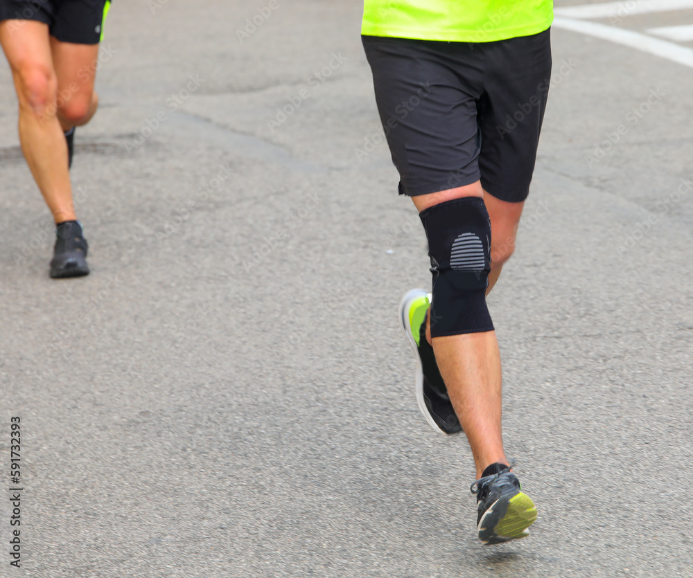 Fototapeta premium runner with kneegiera runs during the running race in the paved road