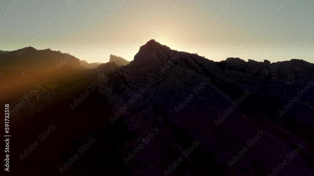 4K aerial drone over backlit mountain peaks at sunset with sun rays shining then revealing the sun 4K aerial drone over backlit mountain peaks at sunset with sun rays shining then revealing the sun