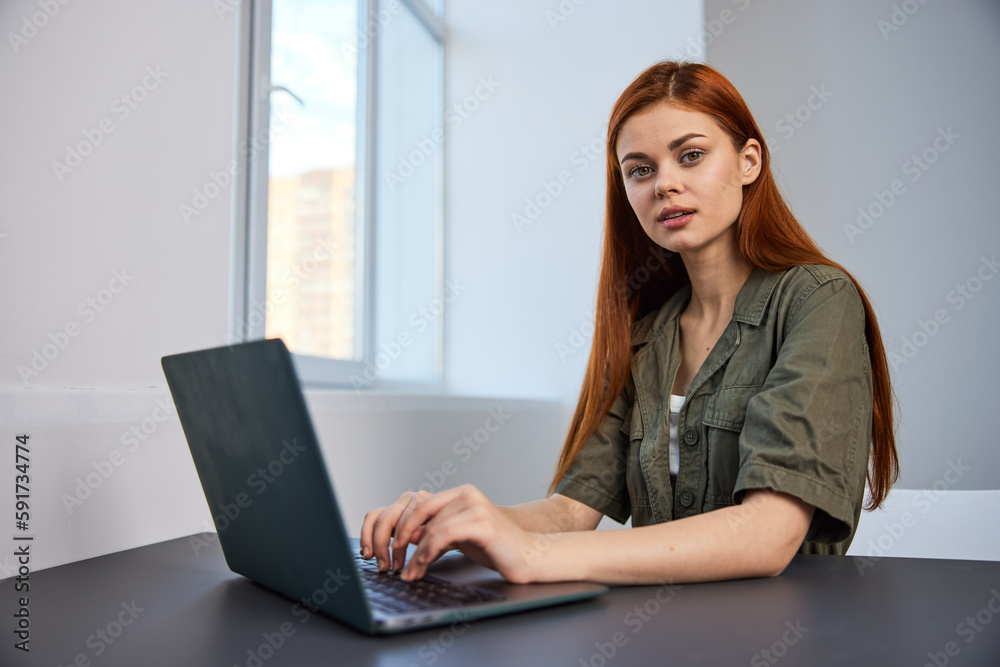 pensive redhead woman sitting at laptop while working in office pensive redhead woman sitting at laptop while working in office