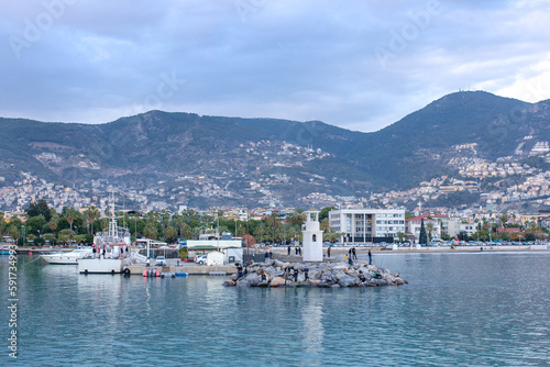 Beautiful view on a town, mountains, sea, lighthouse and ships in Alanya port, Turkey