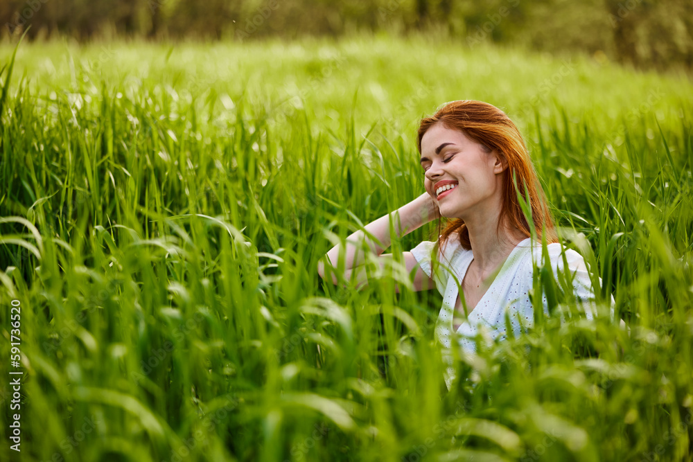 happy woman sitting in tall green grass holding her hair happy woman sitting in tall green grass holding her hair