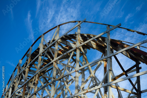 Antique wooden roller coaster against dramatic blue sky