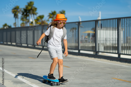 Child on skateboard skating. Young boy on his skateboard striking and practices his skill at the skate park. Happy child having fun on summer holidays.