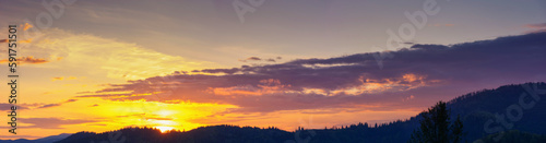 sky panorama at dusk. glowing clouds above the mountain silhouette in evening light