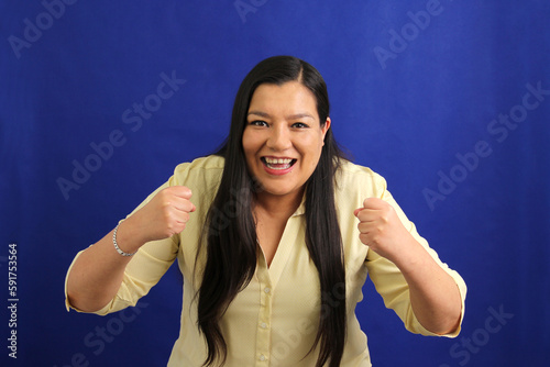 Latin adult woman with very long hair shows herself happy, blissful, lucky, satisfied, full, carefree, dances and shows victory sign 