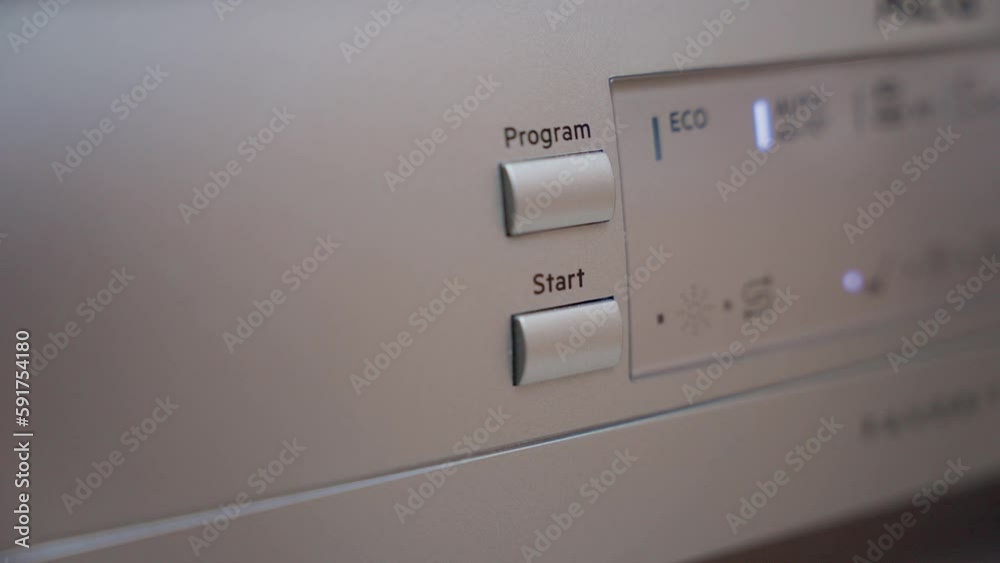 Man Hand Press Start Button on Dishwasher. Starting Dishwasher. Selecting Program On Dishwasher Macro Close up. Man Hand Press Start Button on Dishwasher. Starting Dishwasher. Selecting Program On Dishwasher Macro Close up.
