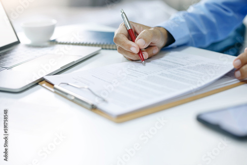 Asian businessman reviewing document reports at office workplace with computer laptop. legal expert, professional lawyer reading and checking financial documents or insurance contract