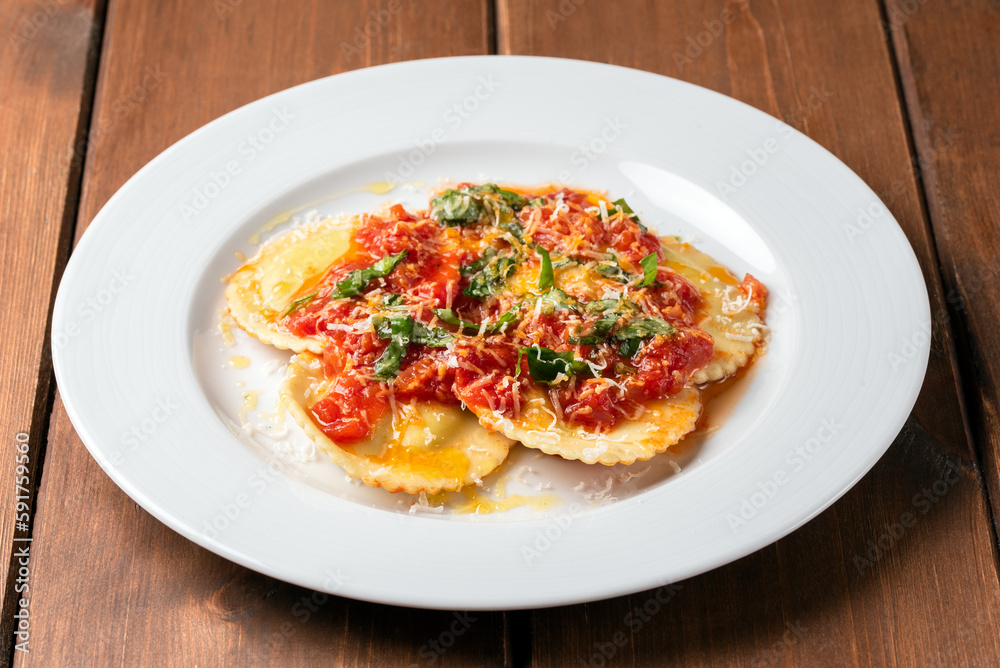 Piatto di deliziosi ravioli al pomodoro e basilico con una spolverata di parmigiano, cibo italiano Piatto di deliziosi ravioli al pomodoro e basilico con una spolverata di parmigiano, cibo italiano