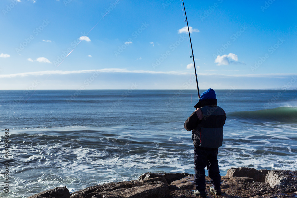 Fisher man fishing with spinning rod at ocean