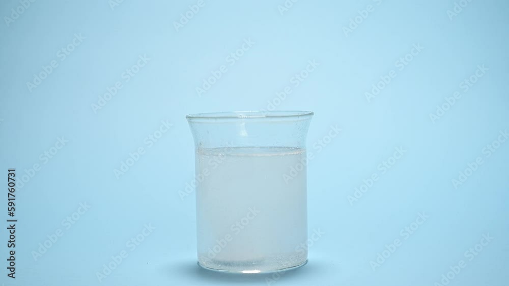 Dissolution of effervescent tablet in glass with water over blue background. Healthcare and medicine. Still life with effervescent pill dissolving in glass of water. Antipyretic. Painkiller. Dissolution of effervescent tablet in glass with water over blue background. Healthcare and medicine. Still life with effervescent pill dissolving in glass of water. Antipyretic. Painkiller.