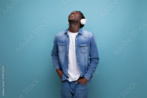 cool dude american man with dreadlocks in denim jacket listening to favorite music playlist with headphones
