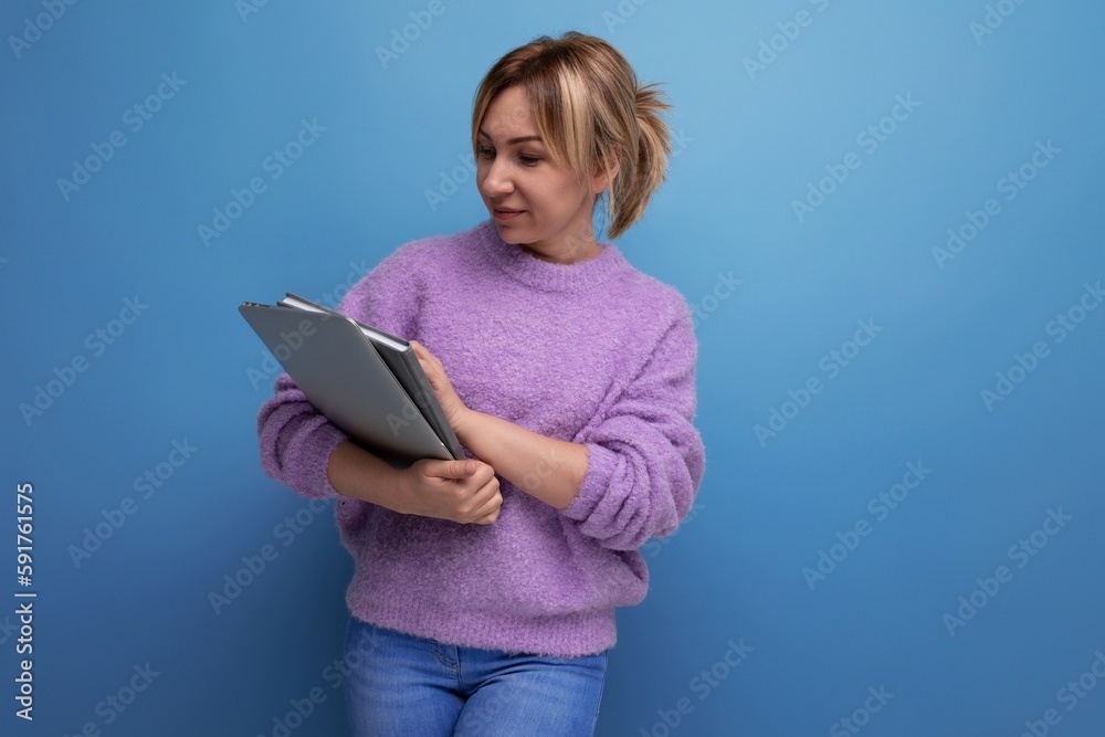 attractive blond millennial woman holding laptop for work on blue background attractive blond millennial woman holding laptop for work on blue background