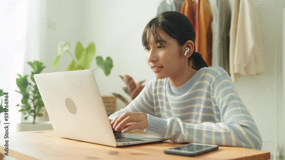 Asian woman working on laptop play social media and listen music using wireless headphones in morning happy Asian woman working on laptop play social media and listen music using wireless headphones in morning happy