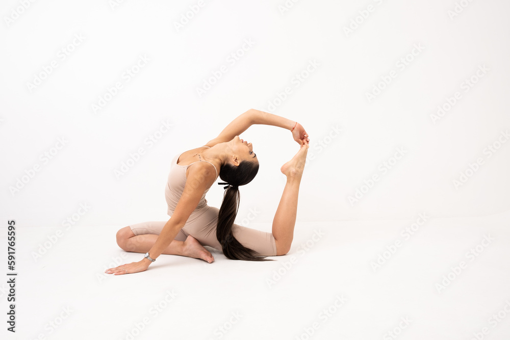 Girl doing stretching in the studio on a white background. A beautiful gymnast with a flexible body and athletic uniform Girl doing stretching in the studio on a white background. A beautiful gymnast with a flexible body and athletic uniform