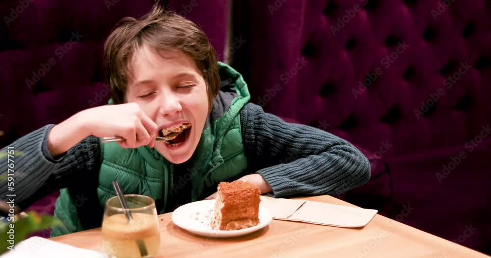 funny boy in a green waistcoat eats a delicious cake with a fork in a cozy interior funny boy in a green waistcoat eats a delicious cake with a fork in a cozy interior