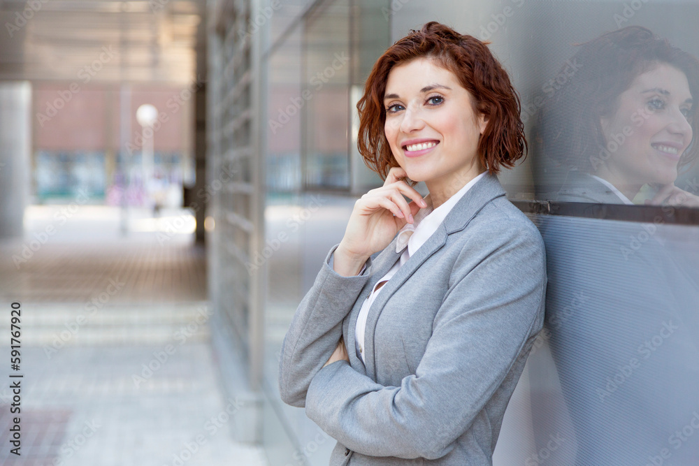 Red-haired businesswoman smiling and touching face outdoors Red-haired businesswoman smiling and touching face outdoors