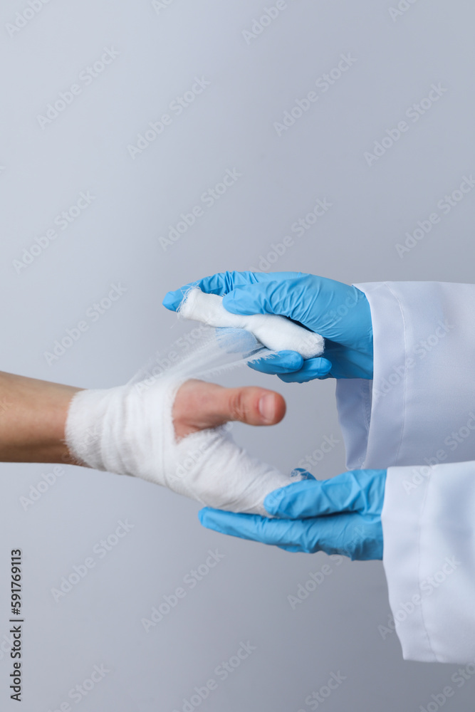 Concept of help during an injury, doctor wrapping hand in bandage on white background Concept of help during an injury, doctor wrapping hand in bandage on white background