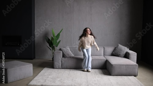 Young woman walk in room and jump on sofa at home