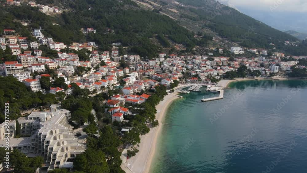 Slow Drone aerial over Brela Beach Croatia calm day, light cloud blue sky Slow Drone aerial over Brela Beach Croatia calm day, light cloud blue sky