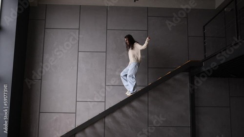 Young woman go down on the stairs at home