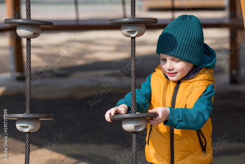 A little boy walks in the spring on the playground. The child is having fun playing outdoors on a sunny spring day. Childhood and child development.